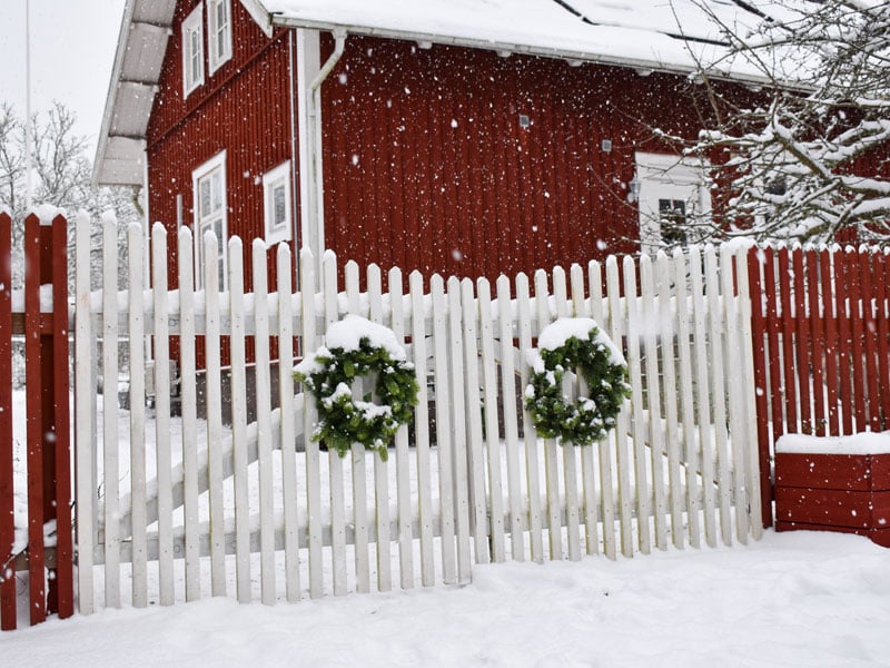 Trädgård i vinterskrud - staket och julkrans